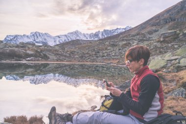 Checking smartphone on scenic mountains clipart