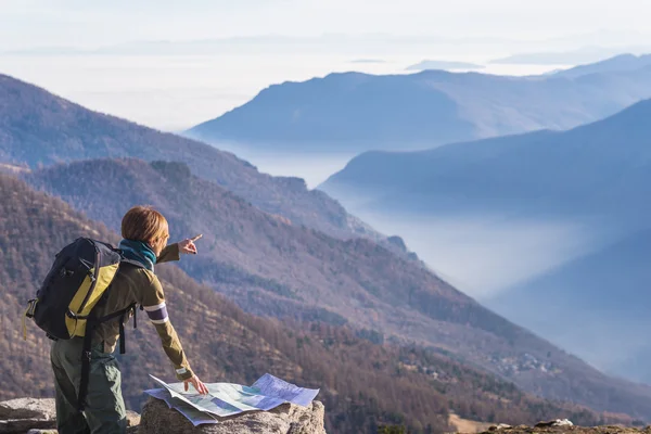 Woman reading trekking map and poiting finger to the Alps — Stock Photo, Image