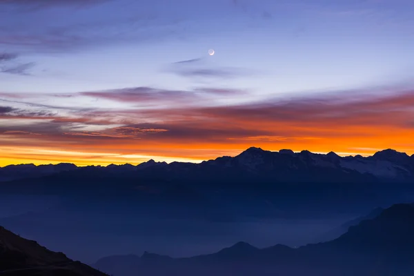 山的轮廓和令人惊叹的天空与月亮在日落 — 图库照片