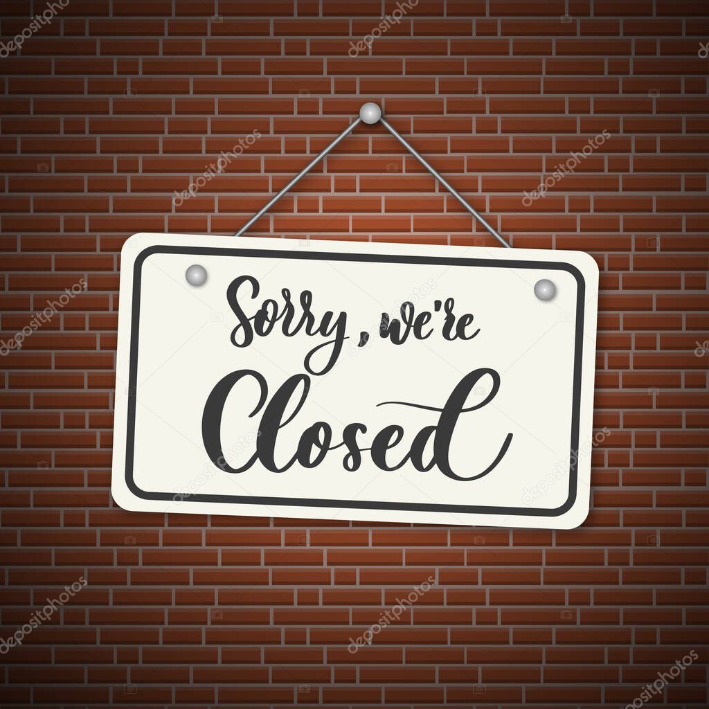 Sorry, we are closed. White sign with shadow isolated on red brick background