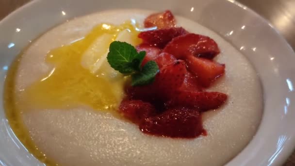 Porridge de semoule aux fruits et à la menthe dans une assiette blanche — Video