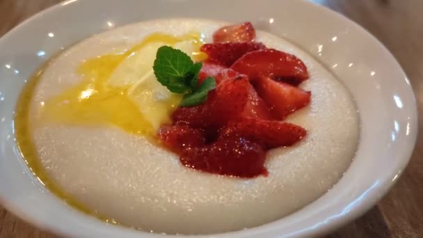 Porridge de semoule aux fruits et à la menthe dans une assiette blanche — Video