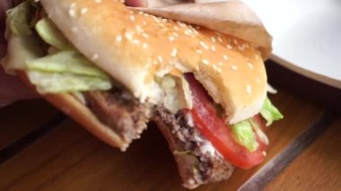 Öğleden sonra bir kafede yakın planda ısırılmış bir hamburger.