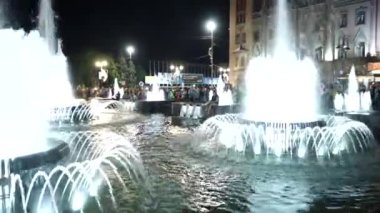 Şehir meydanında gece vakti yanan çeşme.