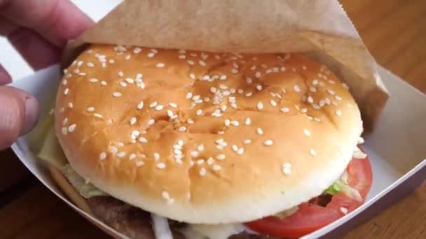 Hamburguesa en mano primer plano por la tarde en un café — Vídeos de Stock