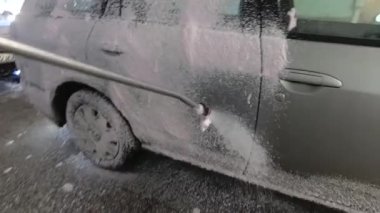 Araba yıkamada gümüş rengi araba yıkamak. Araba beyaz köpükle kaplı.