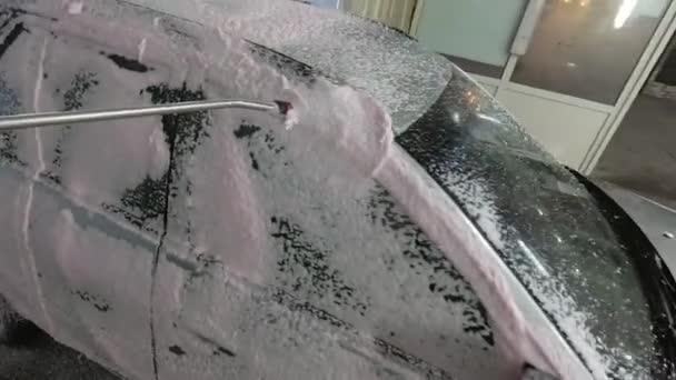 A lavar um carro prateado numa lavagem de carros. O carro é coberto com espuma branca — Vídeo de Stock