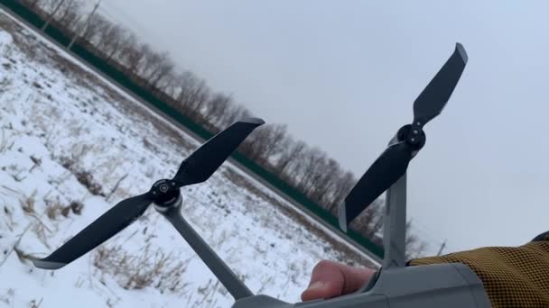 Αρσενικό χέρι σε ένα κίτρινο σακάκι κρατά ένα drone, προπέλες κοντά — Αρχείο Βίντεο