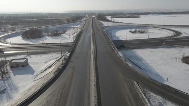 Güneşli bir günde, kışın hareket halindeki arabalarla bir yol kavşağının hava fotoğrafçılığı — Stok video