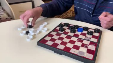 İki adam dama oynamaya hazırlanıyor, taşları tahtaya yerleştiriyorlar.