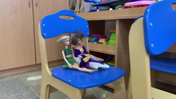 Bebekler çocukların üzerinde oturur. Ahşap sandalyeler ve mavi sırtlar. — Stok video