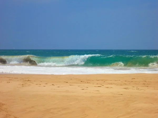 Порожній океанський пляж з жовтим прозорим піском і синіми хвилями — стокове фото