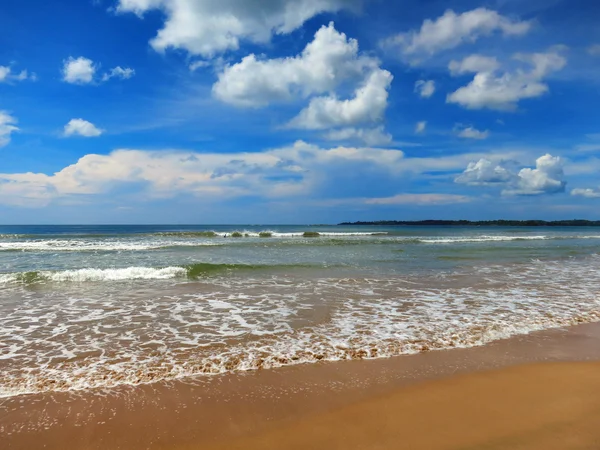 Спокійний тропічний пляж з білим піском і бірюзовою водою під блакитним хмарним небом — стокове фото