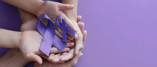 Adult and child hands holding purple ribbons, Alzheimer\'s disease, Pancreatic cancer, Epilepsy awareness, world cancer day on purple background