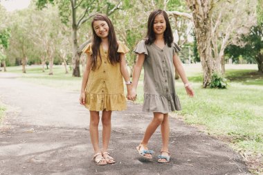 Mutlu ve sağlıklı karışık Asyalı kızlar parkta gülümsüyor, en iyi arkadaşlar ve arkadaşlık ve çeşitlilik kavramı