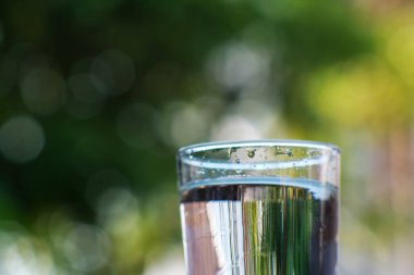 Arka planda bir bardak içme suyu var.