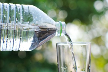 Arka planda bir bardak içme suyu var.