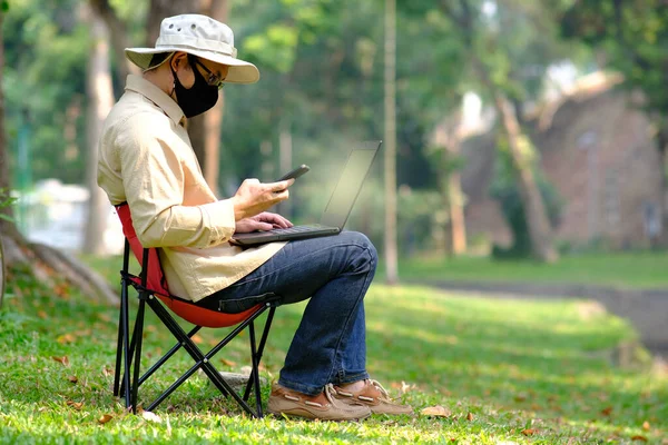 man using laptop computer in garden background and technology concept