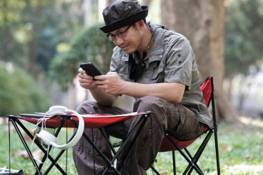 Bahçe arka planında akıllı telefon kullanan ve rahatlayan bir adam