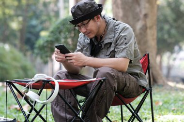 Bahçe arka planında akıllı telefon kullanan ve rahatlayan bir adam