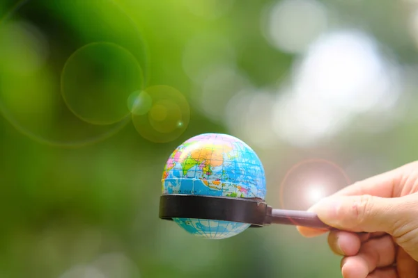 hand holding a green globe with a blurred background