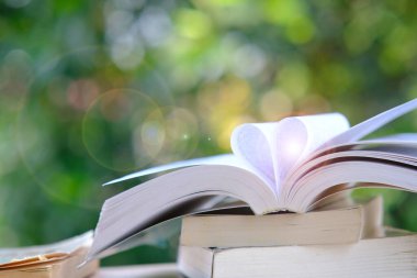 Kütüphanede öğrenim, masa ve alana yığılmış kitap yığınları