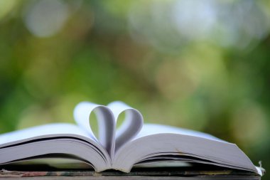 Kütüphanede öğrenim, masa ve alana yığılmış kitap yığınları
