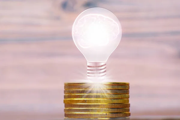 light bulb with coins on wooden background. concept of saving idea.