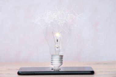 Akıllı telefondaki ampul, fikir yeniliği ve ilham konsepti, gelecekteki yeni teknoloji, fikirler ve düşünme konsepti.