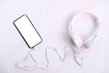 Beyaz arka planda kulaklığı olan modern bir cep telefonu. en üstteki görünüm.