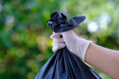 man's hands hold a plastic garbage bag on a green background