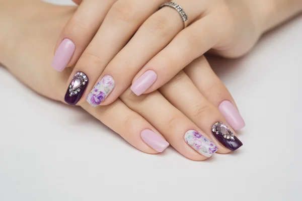 Beyaz arka plan üzerinde mücevher ile manikürlü tırnaklar