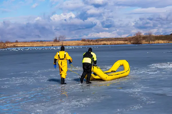 Dalış elbiseli iki itfaiyeci, buz üstünde kurtarma yöntemleri deniyor.