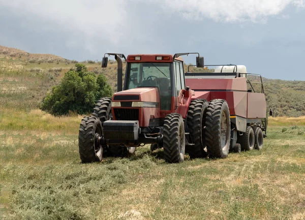 Red tractor on a hay farm bailing hay