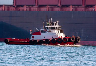 Bir kargo gemisinin yanında giden römorkör.