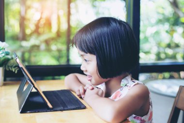 Evde dizüstü bilgisayar kullanan mutlu çocuklar.