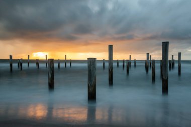Petten 'de Kuzey Denizi' nde kutup köyü ile çekilen uzun bir keşif fotoğrafı, akşam saatlerinde güzel bir turuncu güneş ve ağır bulutlarla çekildi..