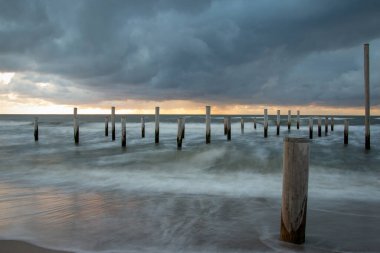 Petten 'de Kuzey Denizi' nde kutup köyü ile çekilen uzun bir keşif fotoğrafı, akşam saatlerinde güzel bir turuncu güneş ve ağır bulutlarla çekildi..