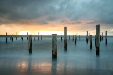 Petten 'de Kuzey Denizi' nde kutup köyü ile çekilen uzun bir keşif fotoğrafı, akşam saatlerinde güzel bir turuncu güneş ve ağır bulutlarla çekildi..