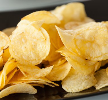 Delicious potato chips on the black plate
