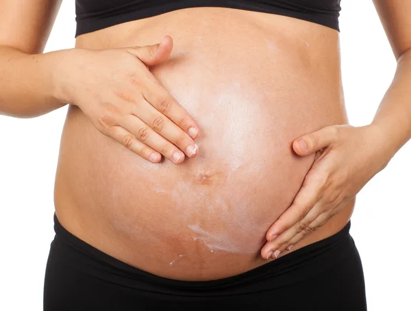 Pregnant woman massaging her belly with ointment against stretch — Stock Photo, Image