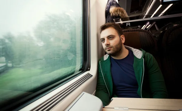 Young man staring out the train window. — Stock Photo, Image