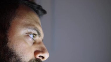 Bilgisayarla uğraşırken bir adamın gözlerini kapat. Gözler farenin hareketini izlerken monitör ışığı vizeyi aydınlatır.