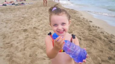 Three year old Caucasian girl plays on the beach, splashing water and running. Concept of fun and vacation