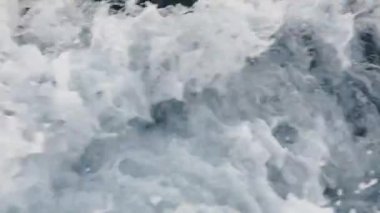 Beyaz köpük üreten bir motorlu teknenin geçişi sırasında deniz suyu sarsılıyor. Mavi su ve beyaz köpüklü doğal soyut arkaplan.