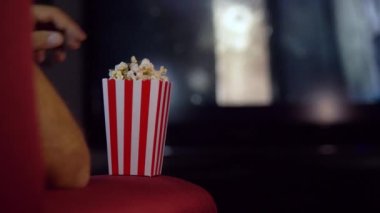 Evde kanepede film izlerken patlamış mısır yemek. Parlak ışıkları olan bir evde sahne, patlamış mısır kokulu bir film gecesi..