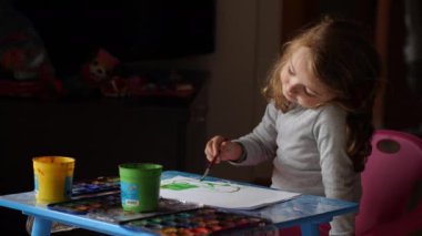 4 yaşındaki kız evde suluboya resimler çiziyor..