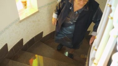 Evde merdivenleri çıkmakta zorlanan kilolu yaşlı bir kadın..