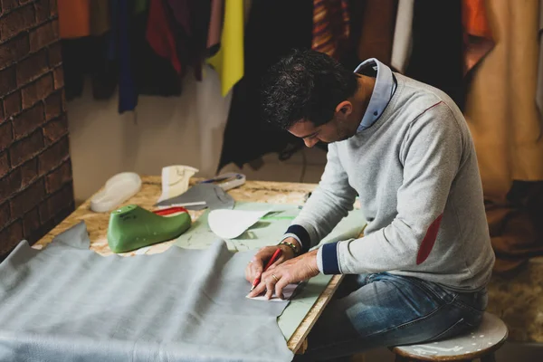 Shoemaker or shoe designer working with leather for the production of handmade shoes.