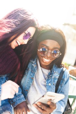 Çok ırklı arkadaşlar bir bahar günü akıllı telefonla eğleniyorlar..